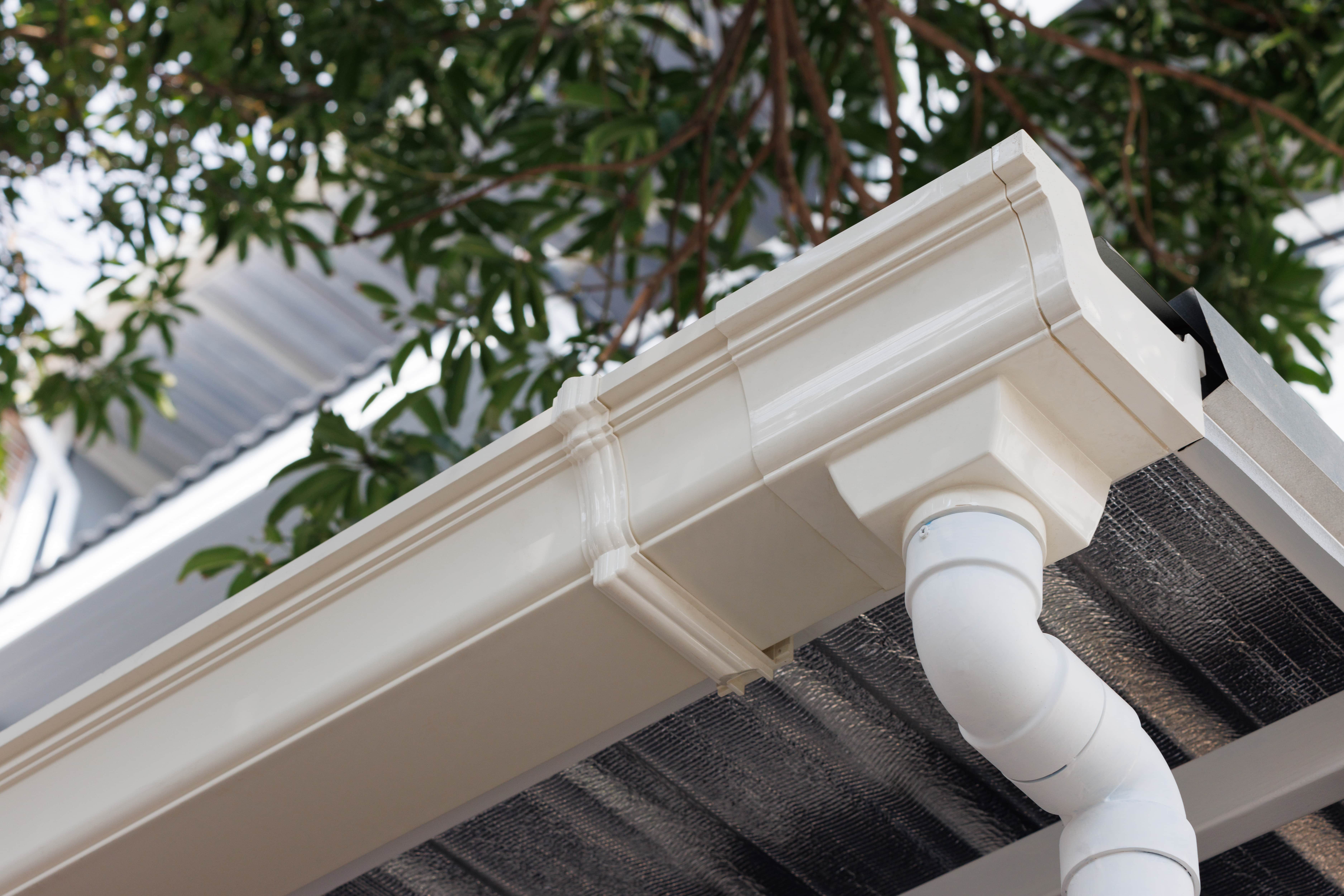 white gutters in a roof with downspout